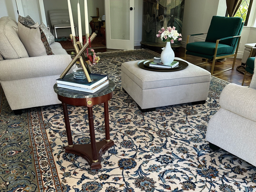 Elegant living room featuring a large handwoven rug with intricate floral patterns and a blue-green border, adding warmth and character to the space.
